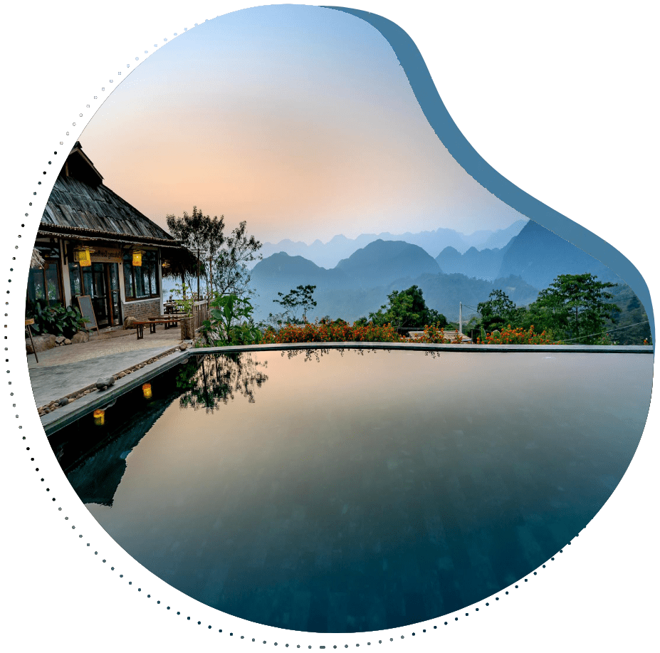 A pool with a hut and mountains in the background